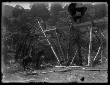 Workers building the timber trestle of a mining flume near Red River in the 1910s, photographed on a glass plate by Robert L. Campbell.